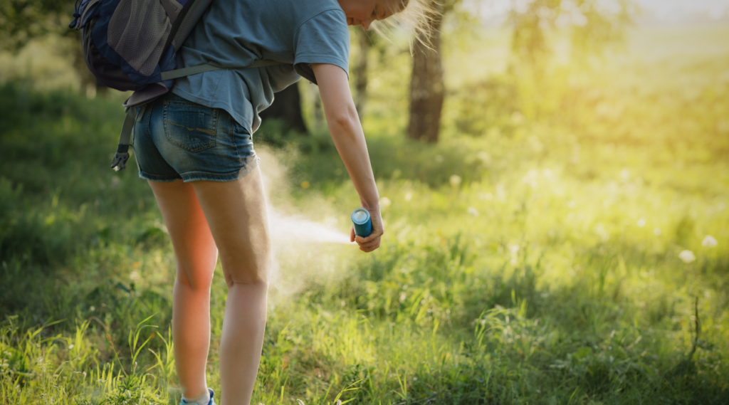 woman spraying mosquito repellent on her legs while hiking picture for blog What Is The Most Effective Natural Mosquito Repellent?