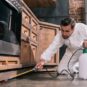 Melbourne specialized pest control expert spraying around kitchen cabinets